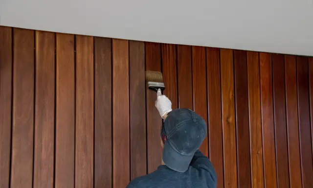 Application d'une finition sur un lambris en bois. Le résultat avant/après est saisissant, révélant la beauté naturelle du bois.