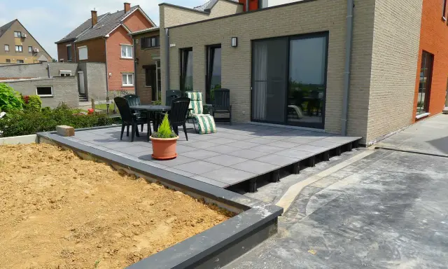 Terrasse avec dalles grises sur plots, prête à accueillir une dalle béton. Table et chaises sur le côté.