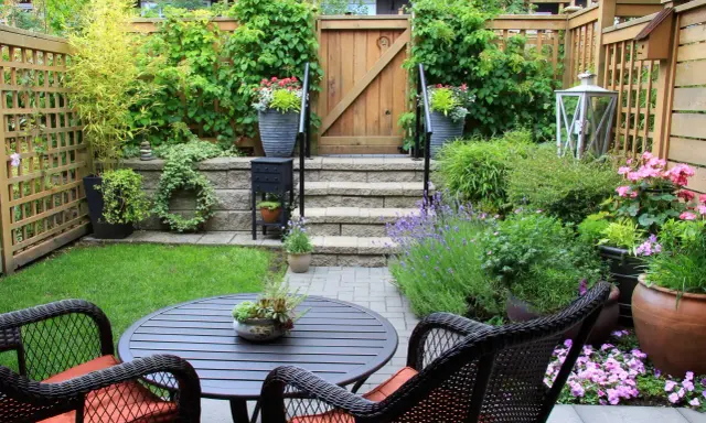 Un petit jardin aménagé avec une table, des chaises, des plantes et une porte en bois.