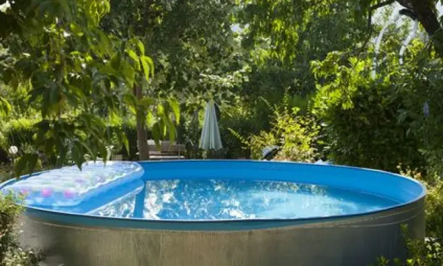 Installation piscine hors sol terminée, prête pour les baignades estivales. Un matelas gonflable flotte sur l'eau bleue.
