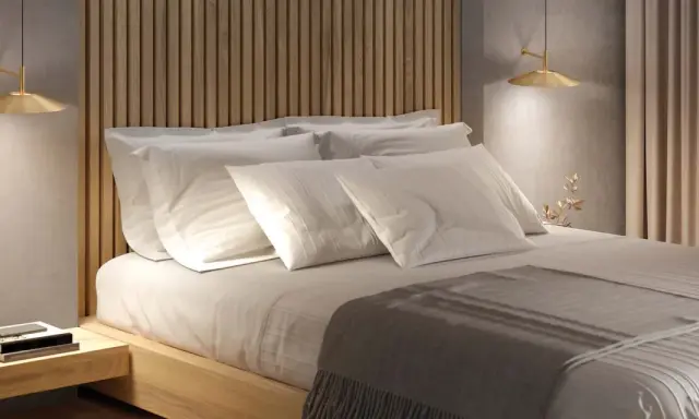 Lit et sa tête de lit en bois, oreillers blancs, lampe dorée. Une ambiance douce pour la deco de chambre.