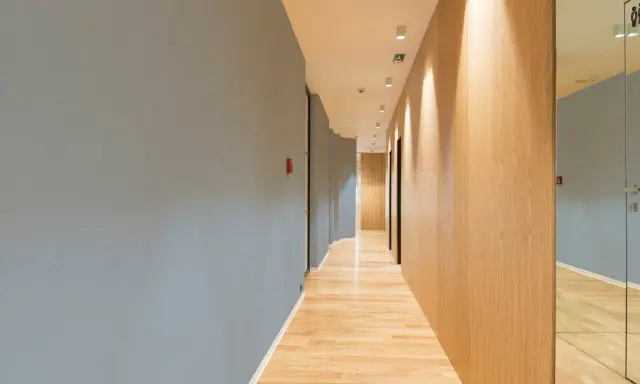Couloir moderne avec un mur bleu texturé, un mur en bois clair et un sol en parquet. Le mur de gauche, en fibre de verre, est d'un bleu doux.