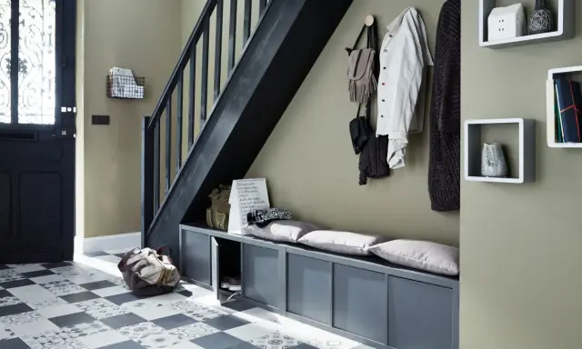 Escalier moderne avec une couleur tendance, banc de rangement gris, porte d'entrée noire et sol à motifs.