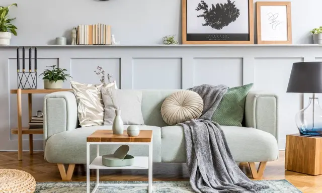 Un plaid gris drapé sur un canapé vert menthe, ajoutant une touche cosy. Idée pour comment mettre un plaid sur un canapé avec style.