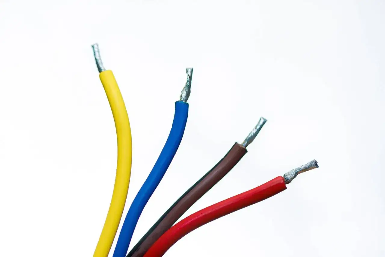 Fils électriques de couleurs vive (jaune, bleu, marron, rouge) prêts à être connectés. Le fil noir est absent, mais l'électricité est présente.