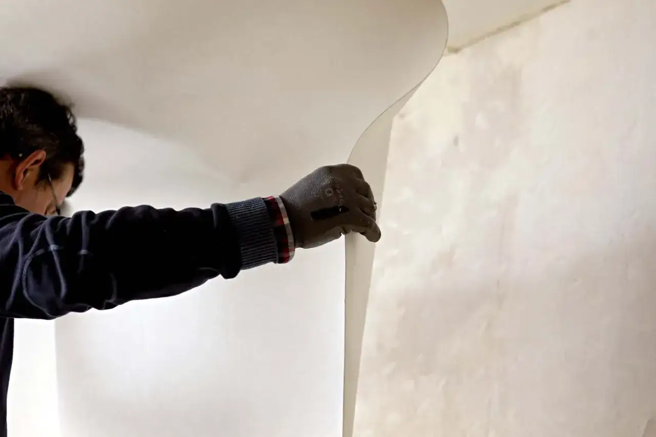 Un ouvrier pose un revêtement mural en fibre de verre sur un plafond.