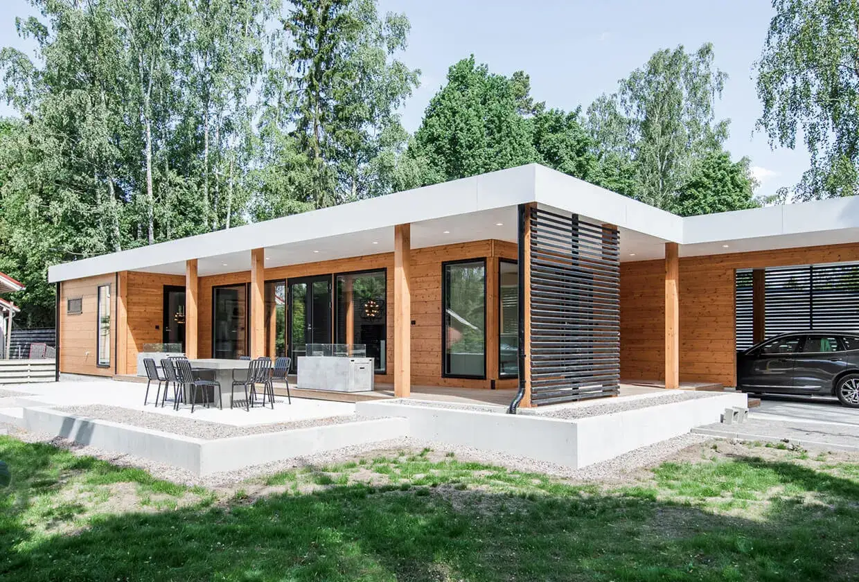 Ce type de maison moderne en bois, avec ses grandes baies vitrées et sa terrasse, s'intègre parfaitement dans un environnement verdoyant.