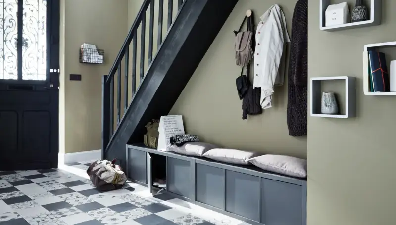 Escalier moderne avec une couleur tendance, banc de rangement gris, porte d'entrée noire et sol à motifs.